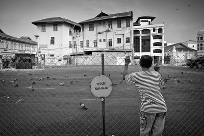 Rear view of boy standing in city against sky