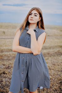 Portrait of beautiful young woman standing on land against sky