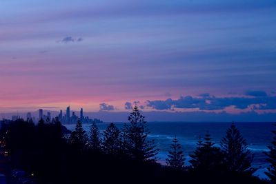 Silhouette trees by sea against sky during sunset