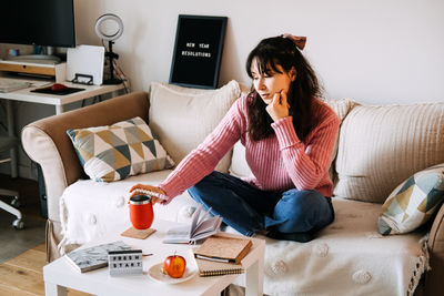 Young woman using phone while sitting at home