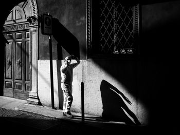 Side view of man standing against wall