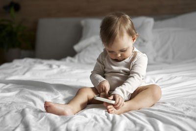 Boy using mobile phone while lying on bed at home