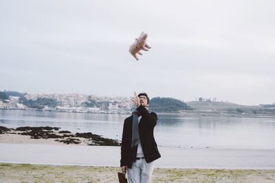 Portrait of man throwing stuffed toy by river