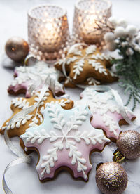 Christmas gingerbread cookies on marble table decorated with garland and candles.