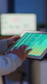 Cropped hand of businesswoman using digital tablet at office