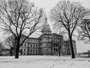 Bare trees and buildings against sky during winter