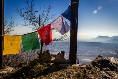 Multi colored flags hanging on mountain against sky