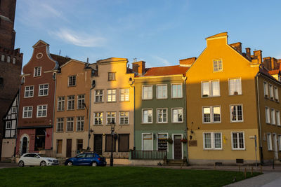Residential buildings by street against sky