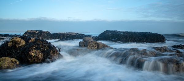 Scenic view of rocks in sea against sky