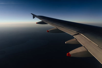 Close-up of airplane flying over landscape against sky