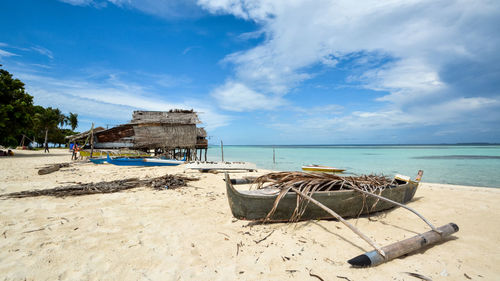 Deck chairs on beach against sky