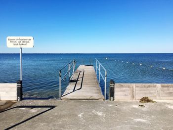 Pier leading towards sea against clear sky during sunny day