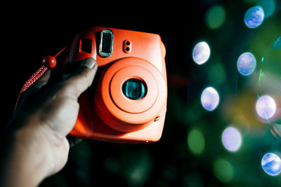 Close-up of hand holding illuminated camera