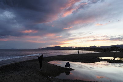 Silhouette person standing on beach against sky during sunset