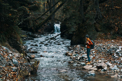 Man standing by waterfall in forest