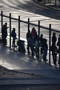 People relaxing on riverbank by sea against sky