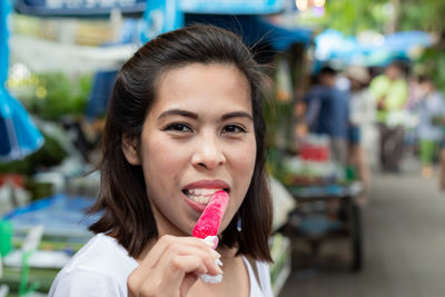 Close-up portrait of woman having pink popsicle outdoors