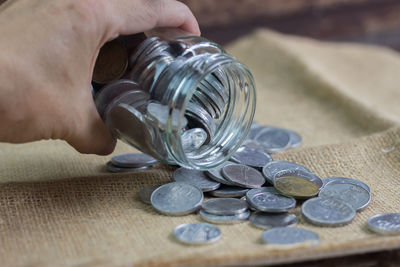Close-up of human hand holding coins on table