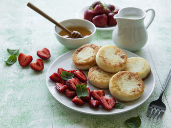 Cottage cheese pancakes, ricotta fritters on ceramic plate with fresh strawberry. 