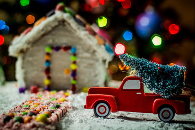 Close-up of toy car on illuminated christmas tree at night