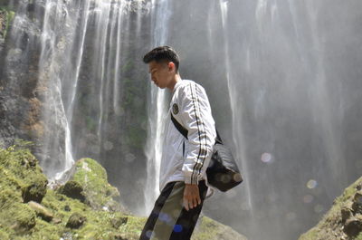 Side view of young man looking at waterfall