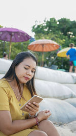 Young woman using mobile phone while sitting outdoors