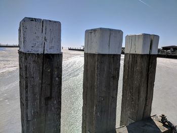 Wooden posts on beach against clear sky