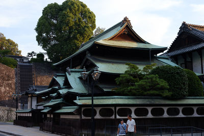 Rear view of man standing outside temple against sky