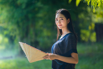 Portrait of smiling young woman holding hat