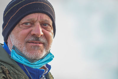 Senior man wearing mask looking away while standing outdoors