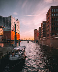 Canal amidst buildings against sky during sunset