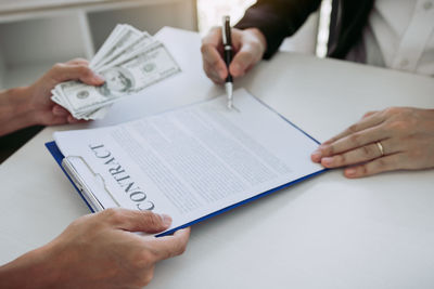 Midsection of man holding paper with text on table