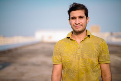 Portrait of young man standing on land against sky