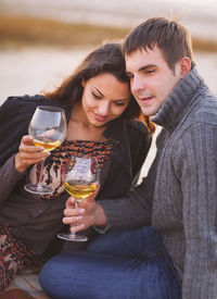 Young couple holding glass while sitting outdoors