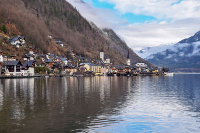 Scenic view of lake by buildings and mountains against sky