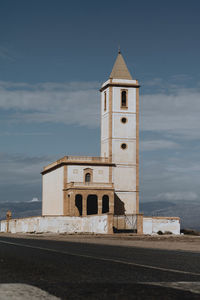 Lighthouse by sea against sky