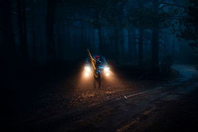 Man standing on road in forest at night