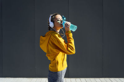 Full length of a man drinking glass against wall
