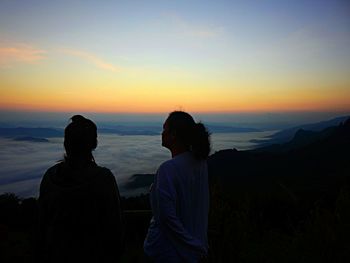 Silhouette people looking at sunset