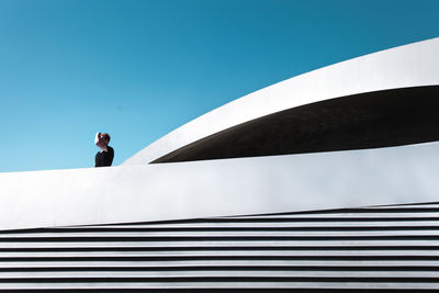 Low angle view of man using mobile phone against sky