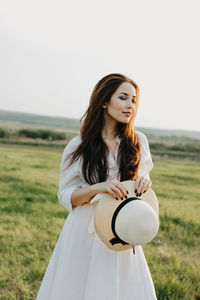 Beautiful young woman standing on land against sky