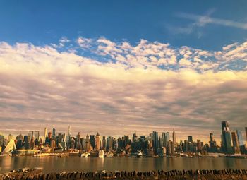 City at waterfront against cloudy sky