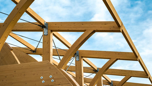 Detail of a modern wooden architecture in glued laminated timber on a blue cloudy sky