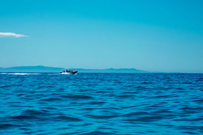 Boat sailing in sea against blue sky