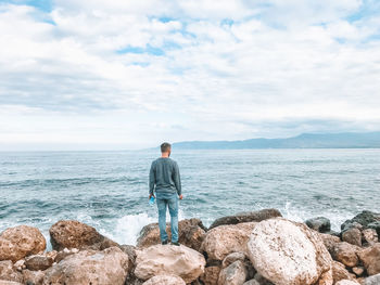 Rear view of man looking at sea against sky