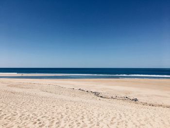 Scenic view of beach against clear blue sky