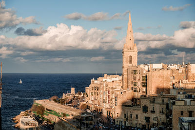 Buildings by sea against sky in city