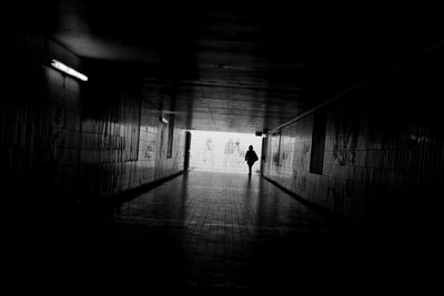 Silhouette of man walking in illuminated tunnel