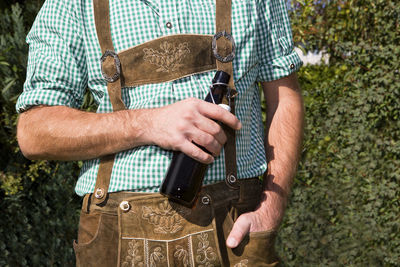 Closeup of a bavarian with bottle of beer outside