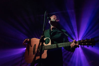 Man playing guitar on illuminated stage